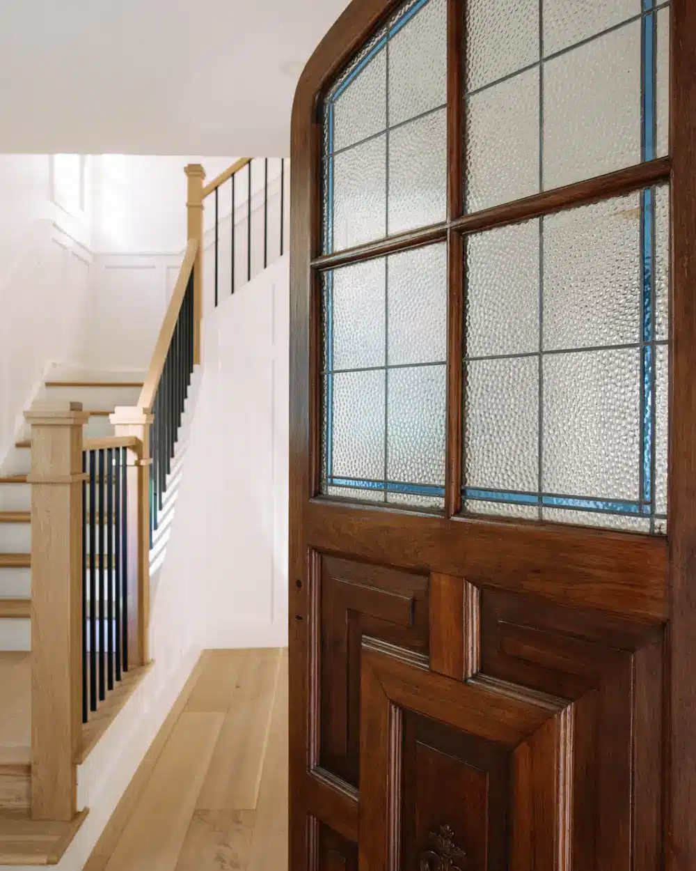 Stained-glass wood door opening to a staircase — The Columbia Project