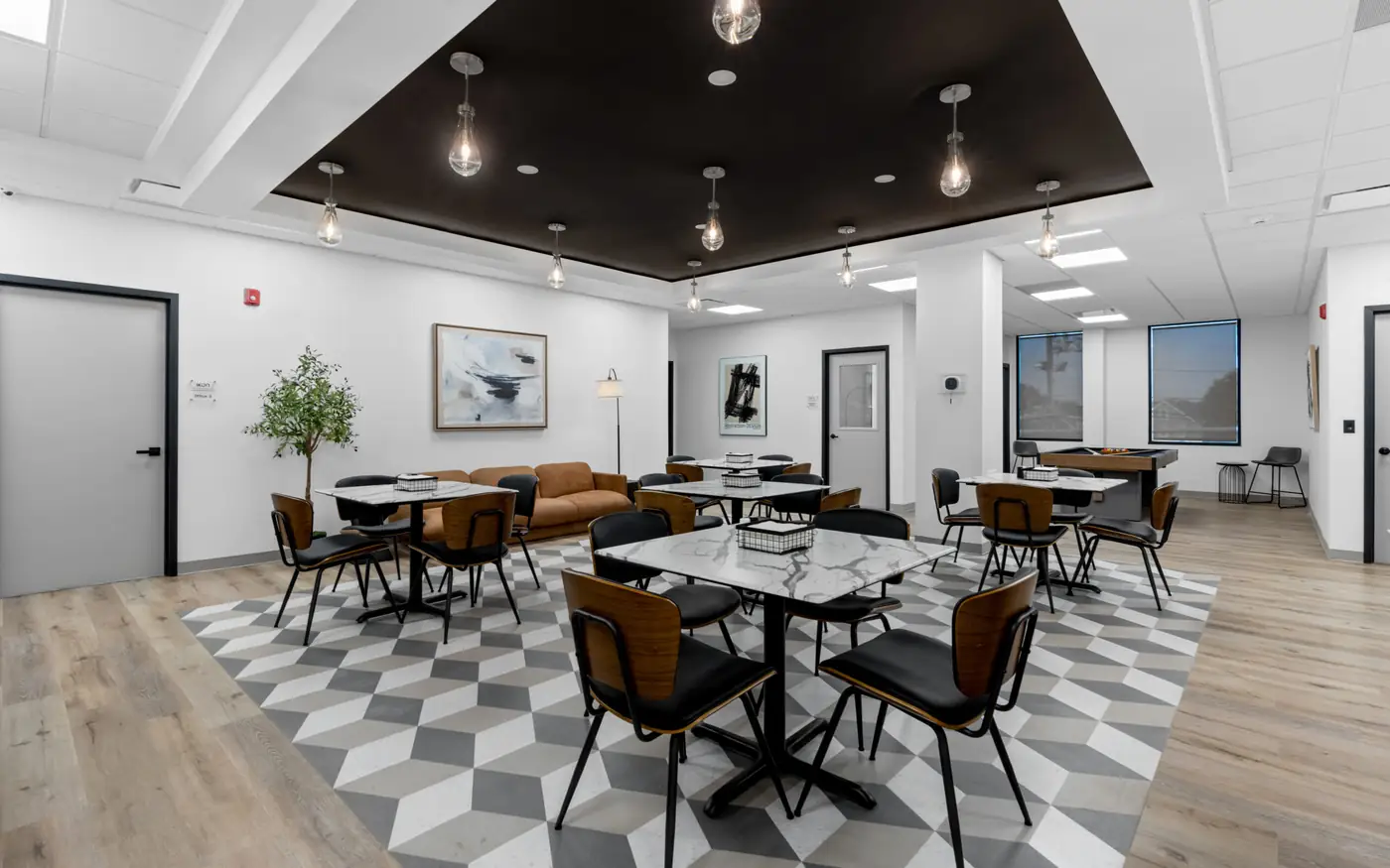 Commercial build-out with lounge seating, dining area and dark coffered ceiling — Ikon Recovery Center