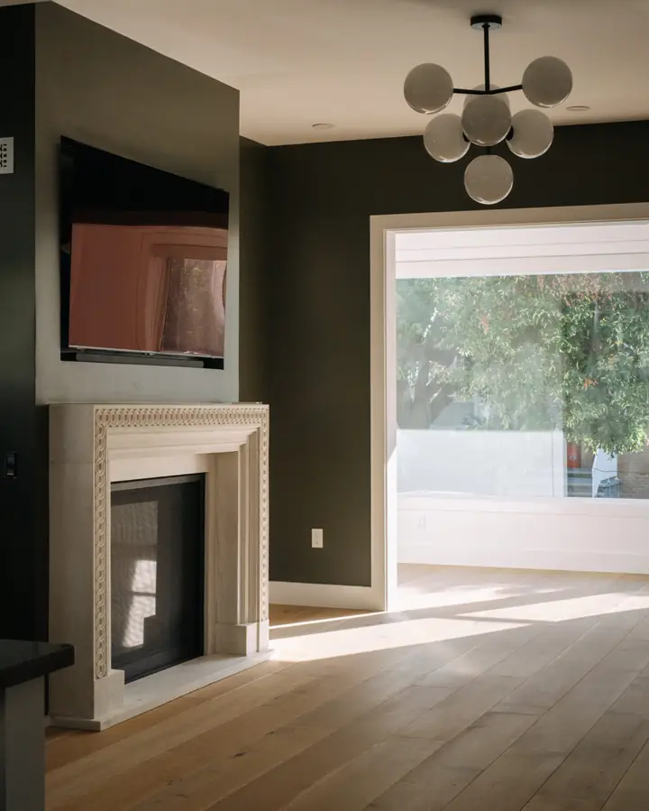 Living room with a carved stone fireplace surround and dark accent wall — The Columbia Project